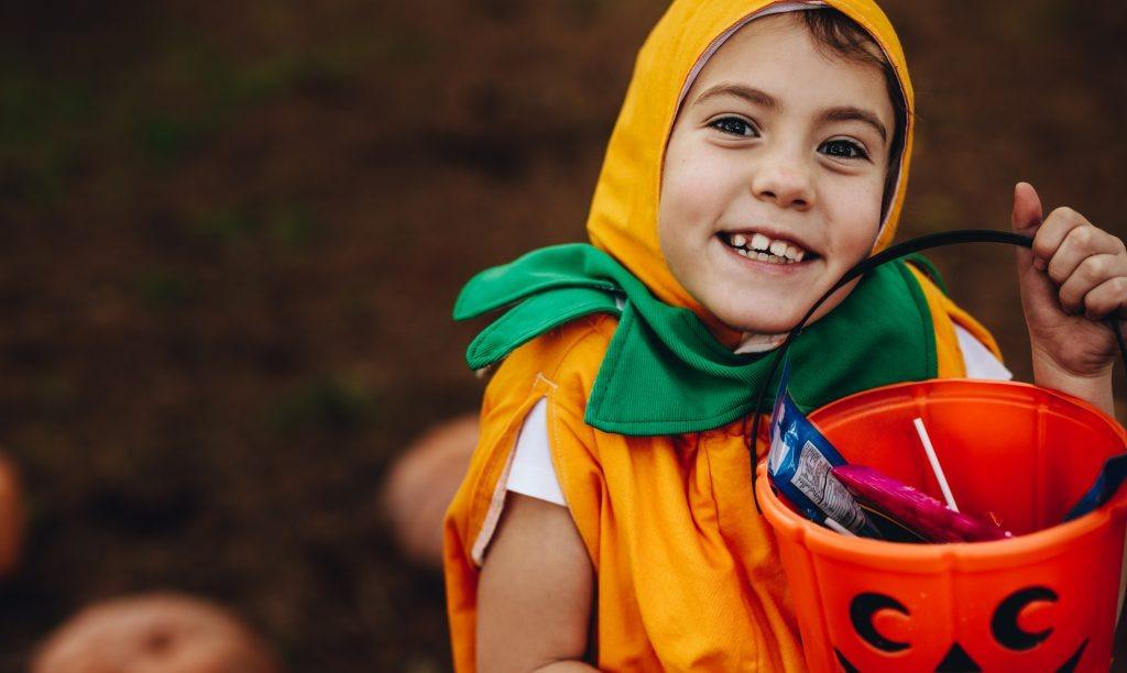 a young girl who is wearing a halloween costume out trick or treating outdoors